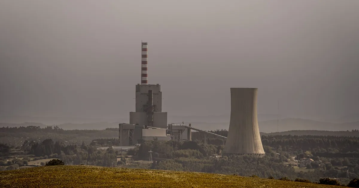 A coal-fired power plant emits smoke on an overcast day, highlighting energy and environmental issues.