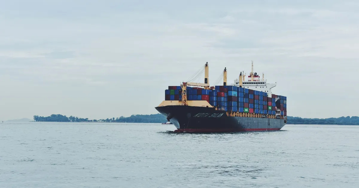 Large cargo ship transporting containers across a calm sea, symbolizing global logistics.
