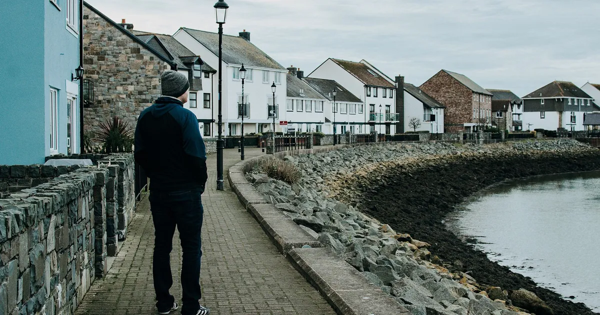 A man walking by seaside cottages on a cloudy day. Peaceful coastal scenery.