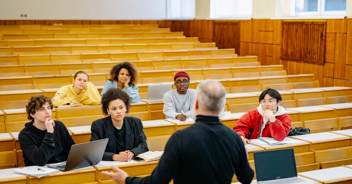 Professor teaching a diverse group of students in a university lecture hall.