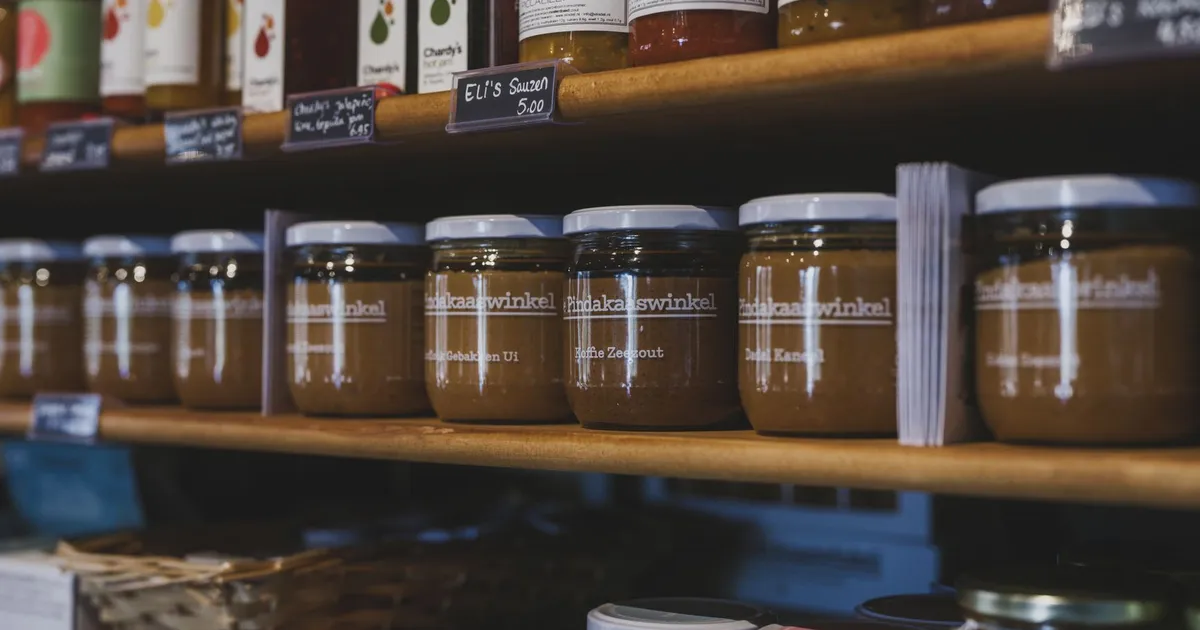 Close-up of artisanal food jars on wooden shelves in a local shop in Almere, Nederland.