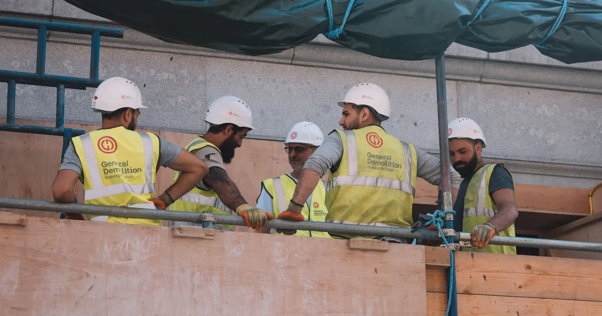 Group of construction workers in safety gear collaborating at a city construction site.