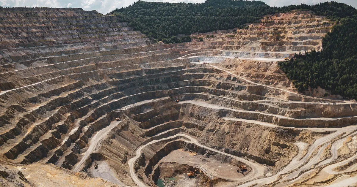 Aerial view of a large open-pit mine with terraced excavation during summer.