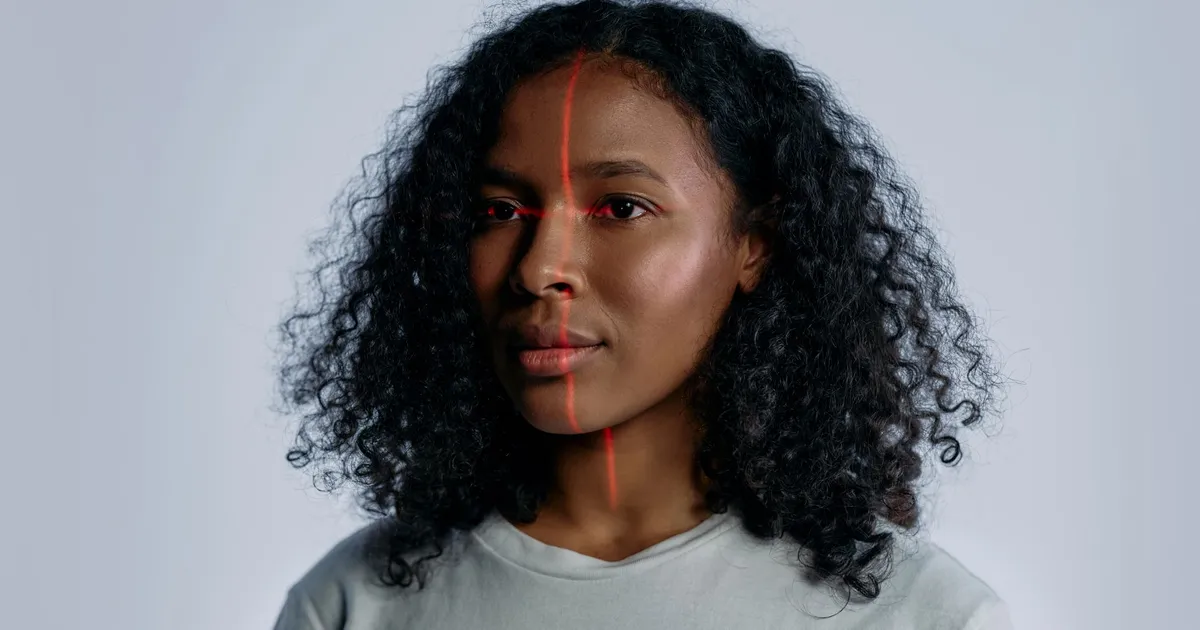 Portrait of a woman with facial recognition technology lines across her face on a plain background.