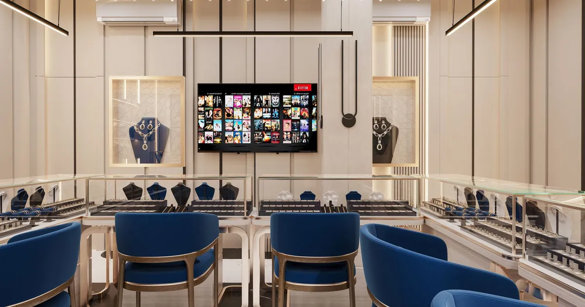 Modern jewelry store interior with elegant lighting and blue seating, showcasing luxury items in display cases.