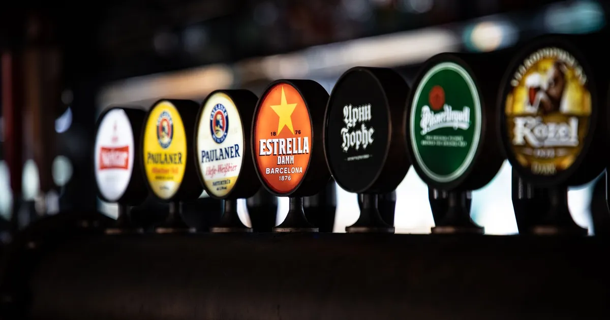 A variety of beer taps featuring distinct brand labels in a row at a bar setting.