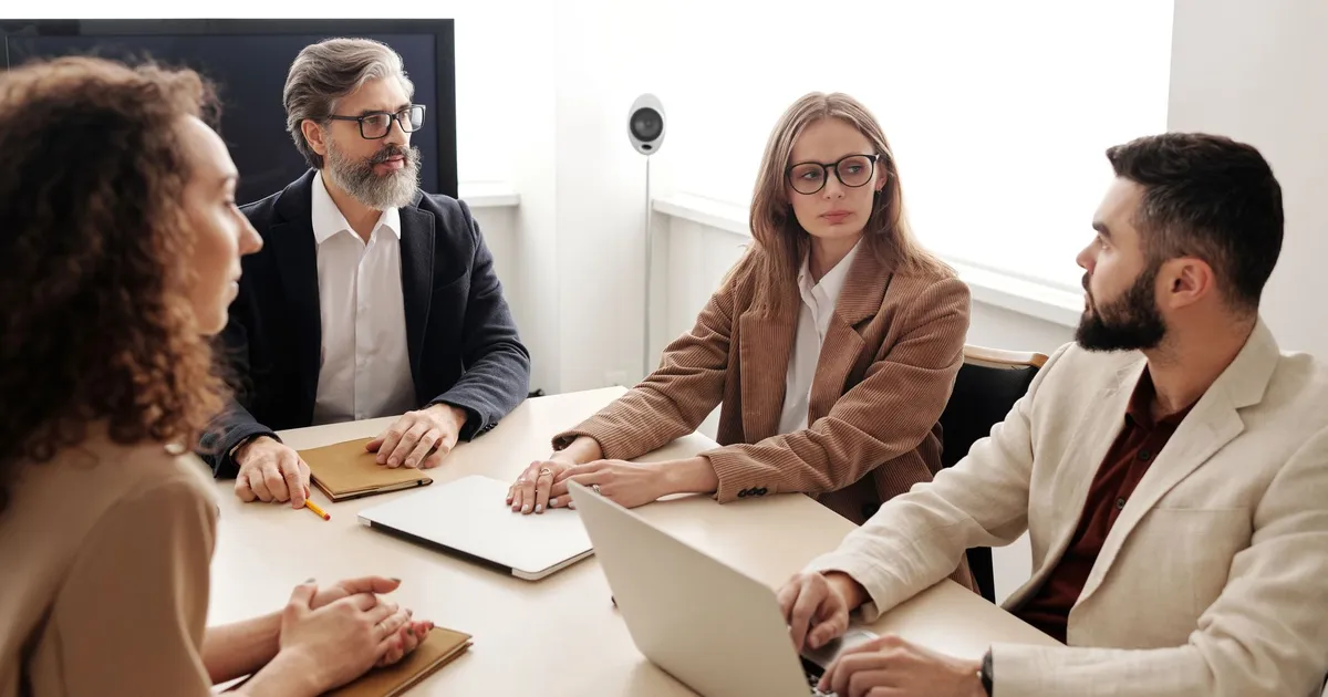Business colleagues engaged in a serious discussion around a conference table.