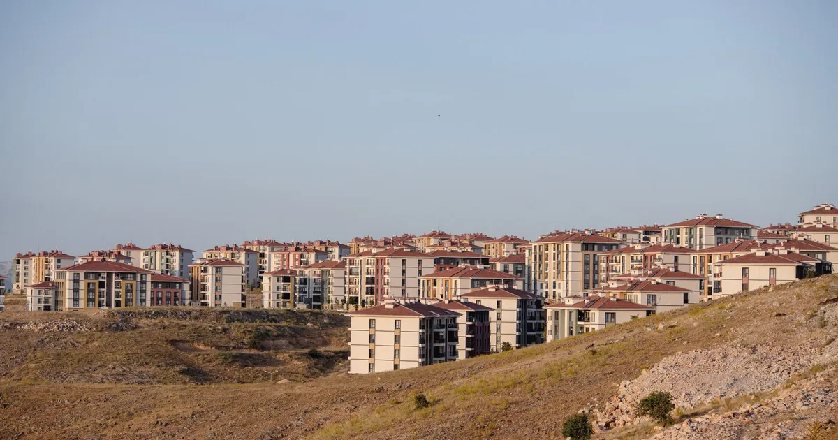 A cluster of modern residential buildings on a hilly landscape during the day.