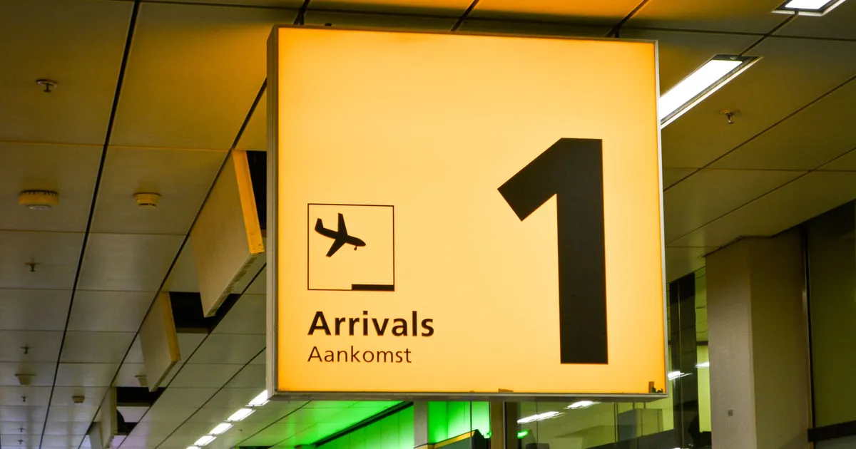 Bright arrivals sign with airplane symbol in an airport terminal.