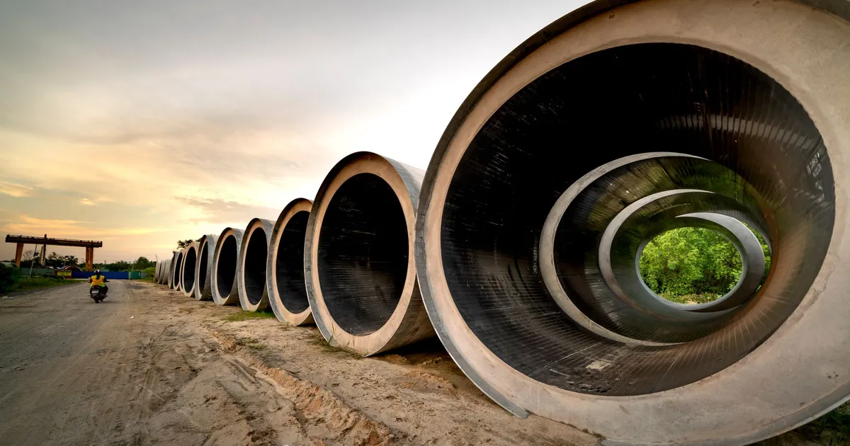 Massive concrete pipes aligned at a construction site during sunset, showcasing an industrial landscape.