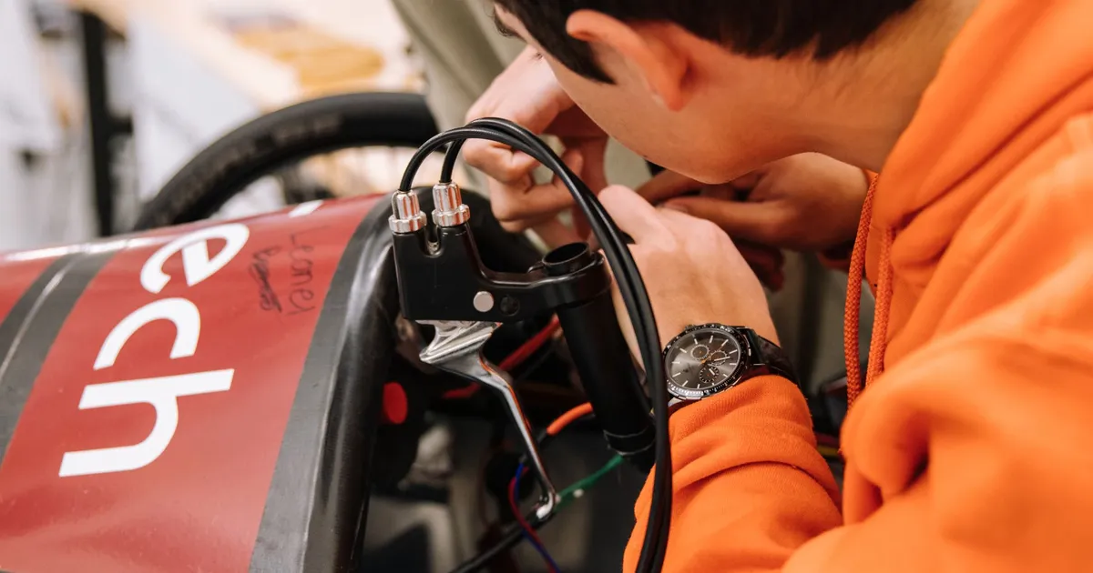 Teenager focusing on an electric car project in a modern engineering workshop, showcasing STEM education.