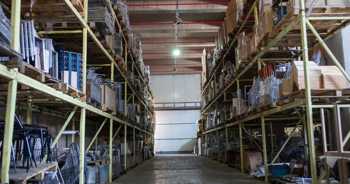 Wide aisle in a spacious warehouse filled with industrial metal shelving units.