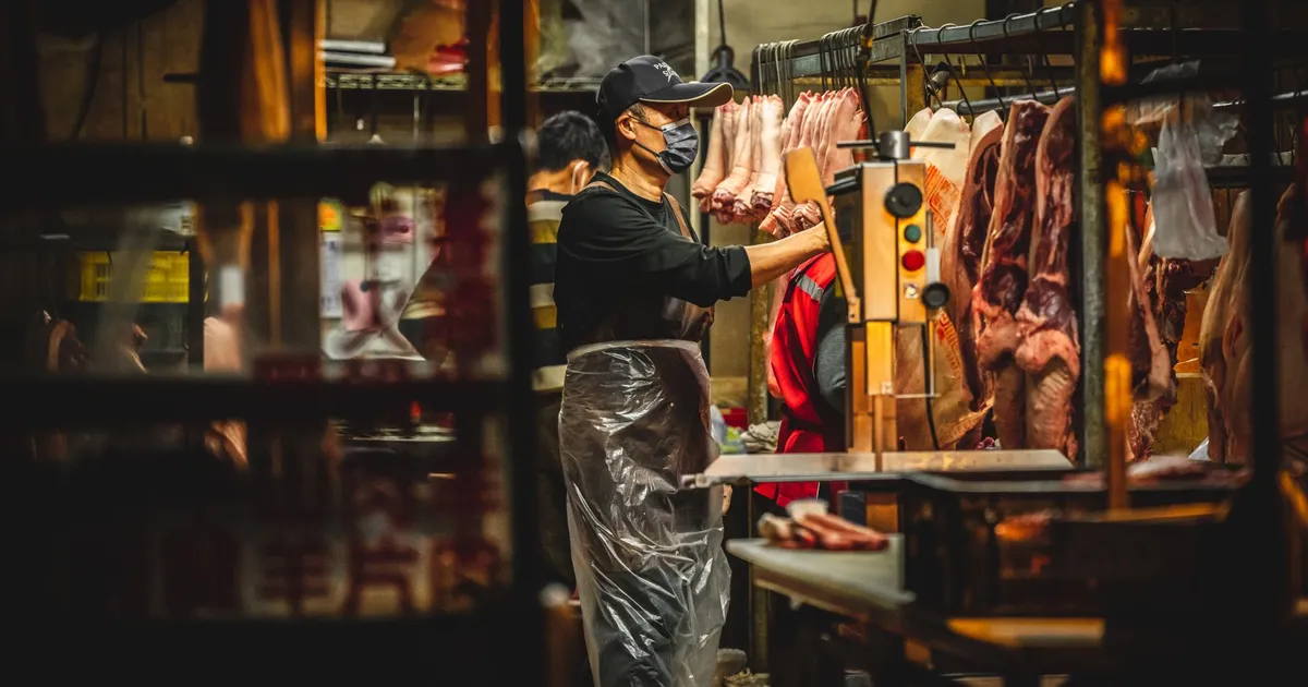 Butchers working in a Miaoli, Taiwan meat market, handling fresh pork.
