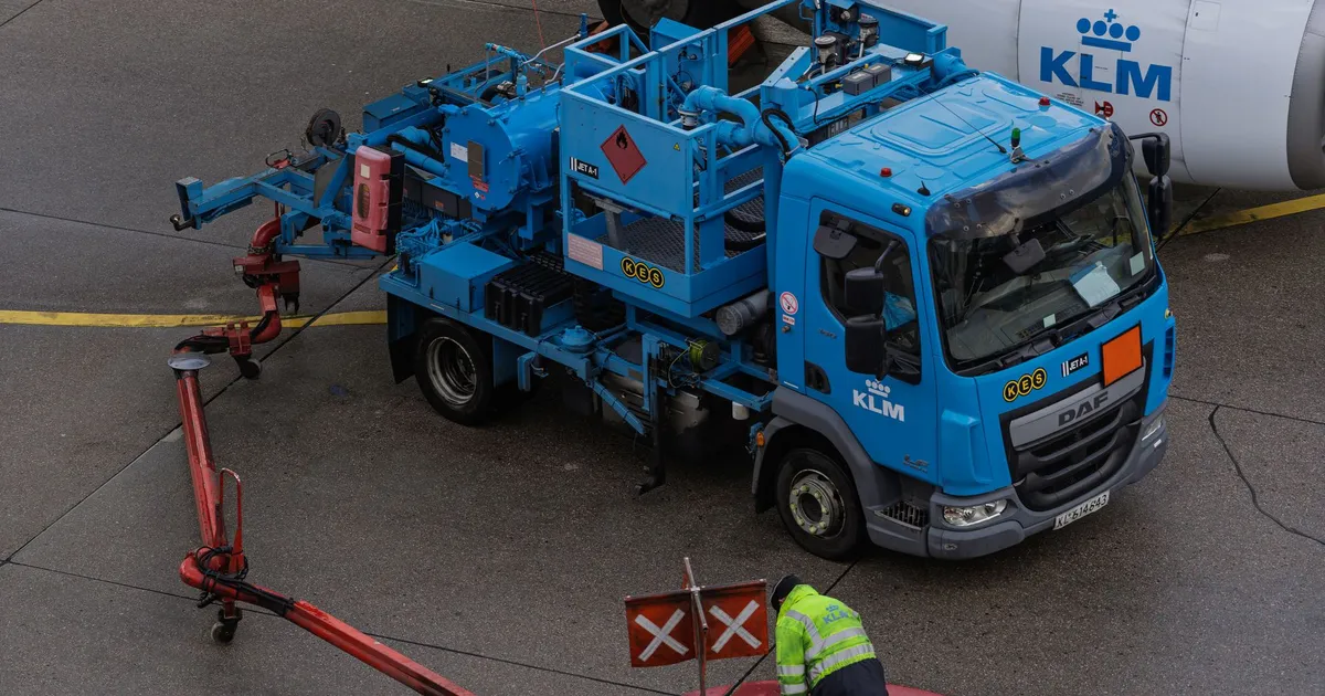 Ground crew at work refueling a KLM airplane with specialized equipment at an airport apron.