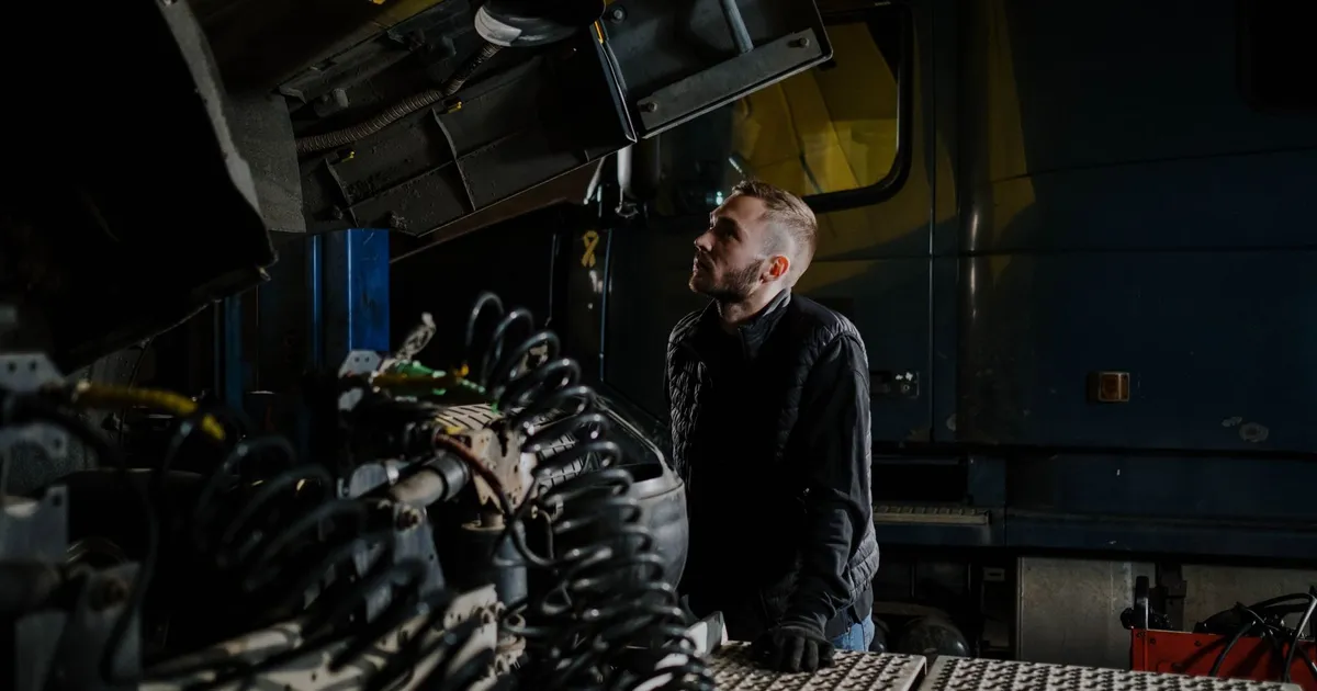 A truck mechanic carefully examines an engine inside a garage shop.