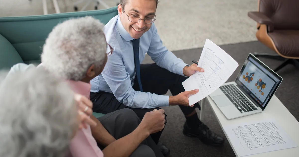 Financial advisor discussing documents with senior clients in an office setting, showcasing a collaborative consulting session.