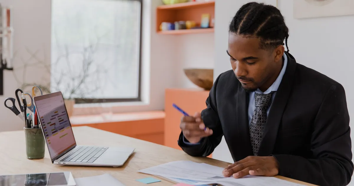 A professional businessman working at his desk, reviewing documents in a modern office environment.