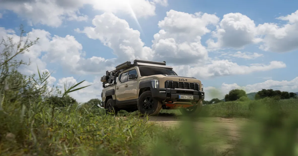 A rugged Kia offroad vehicle navigating a scenic countryside under a partly cloudy sky.