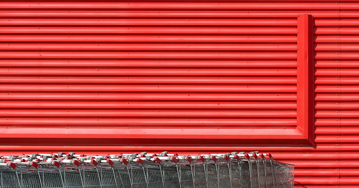 A vibrant red building facade with aligned metal shopping carts in front.