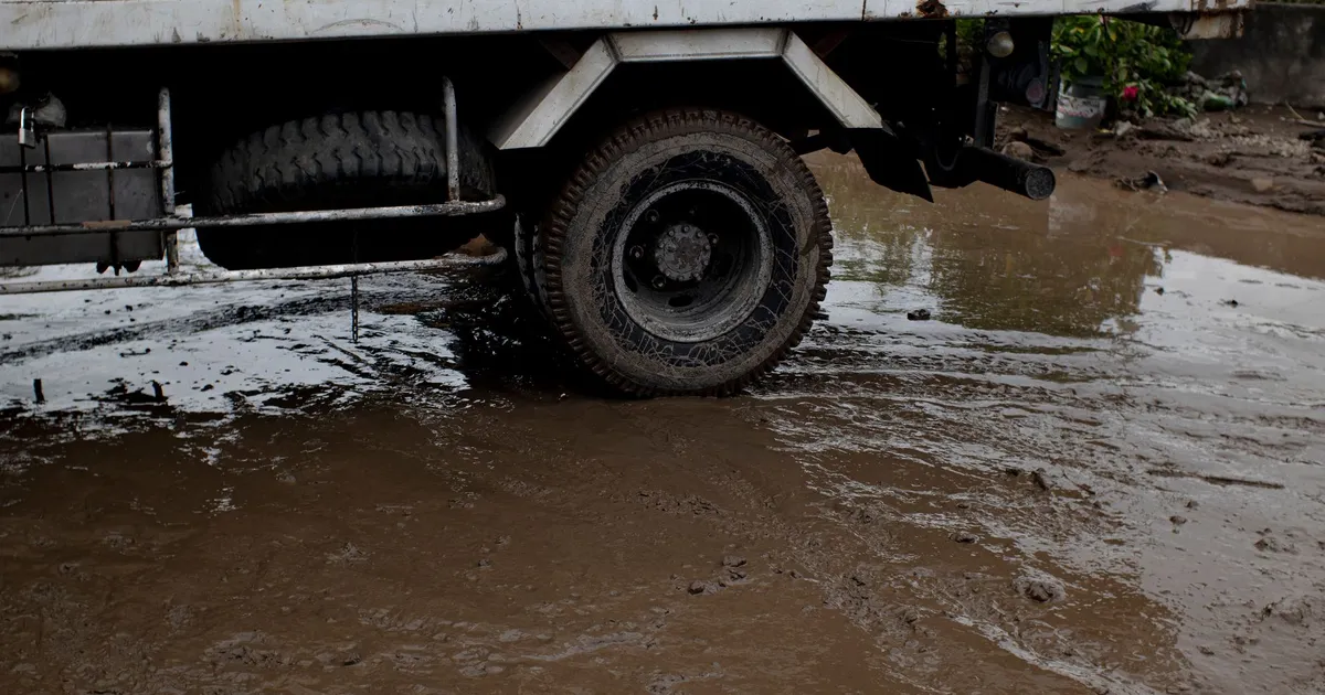 Old transport with rusty surface on roadway with rippled puddle and mud in daylight
