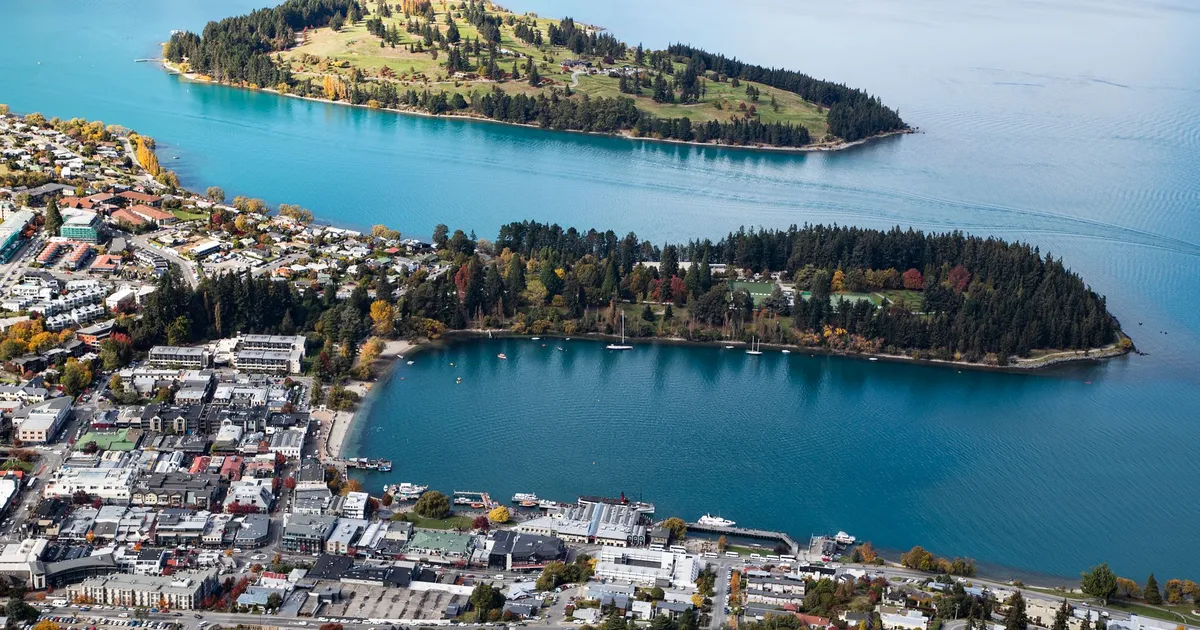 Stunning aerial view of a picturesque town by a lake, featuring lush islands and vibrant fall colors.