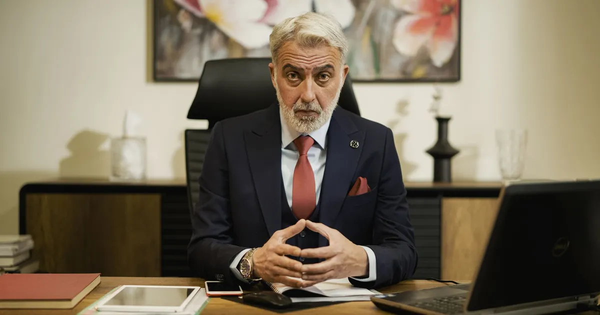 Professional middle-aged businessman sitting confidently at his executive desk in an office setting.