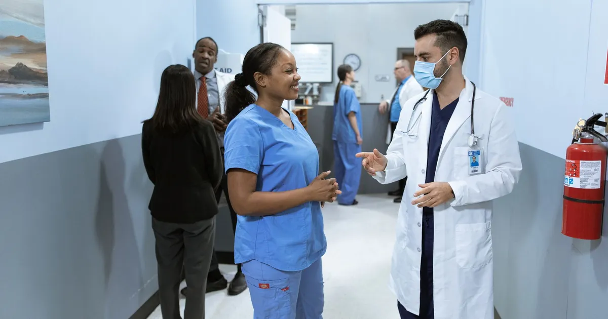 Doctors and nurses in a hospital hallway discussing medical matters.