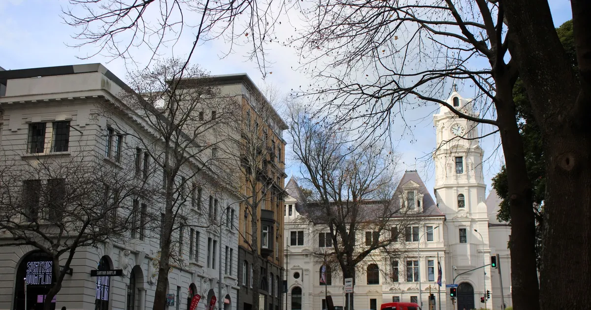 A classic city street with historic buildings and bare winter trees on a bright day.