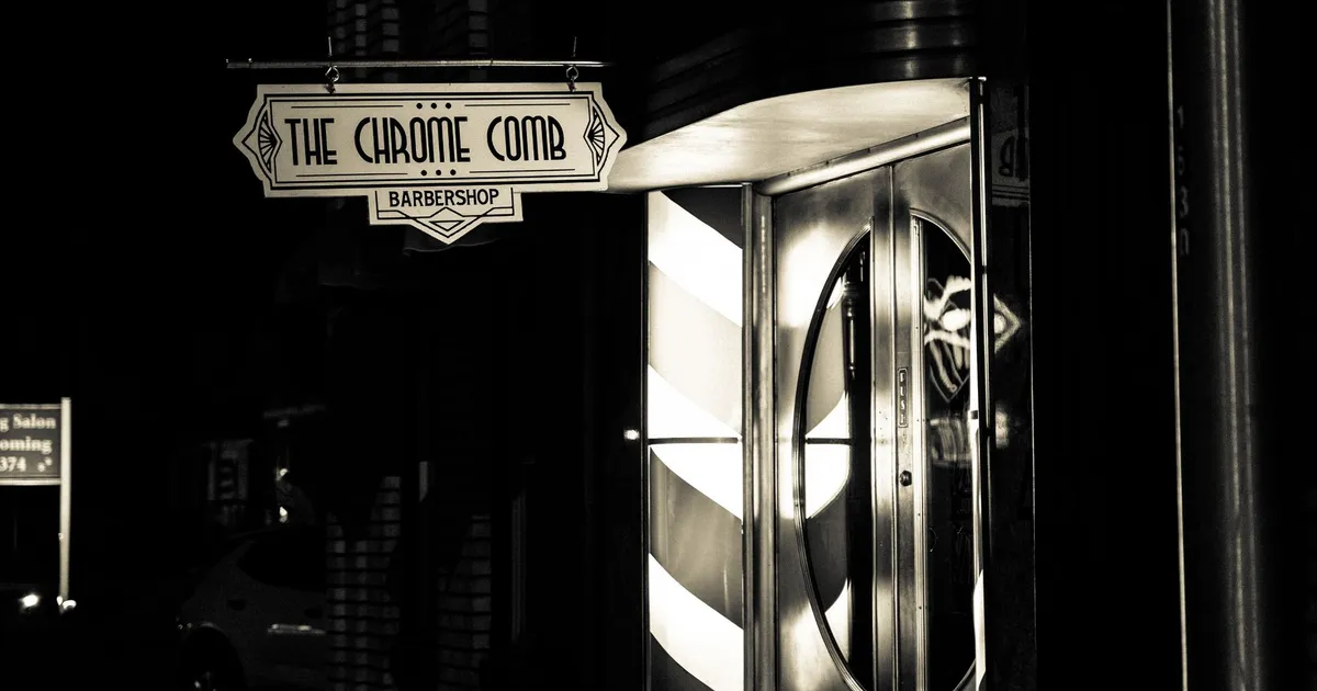 Vintage art deco barbershop entrance captured in monochrome at night.