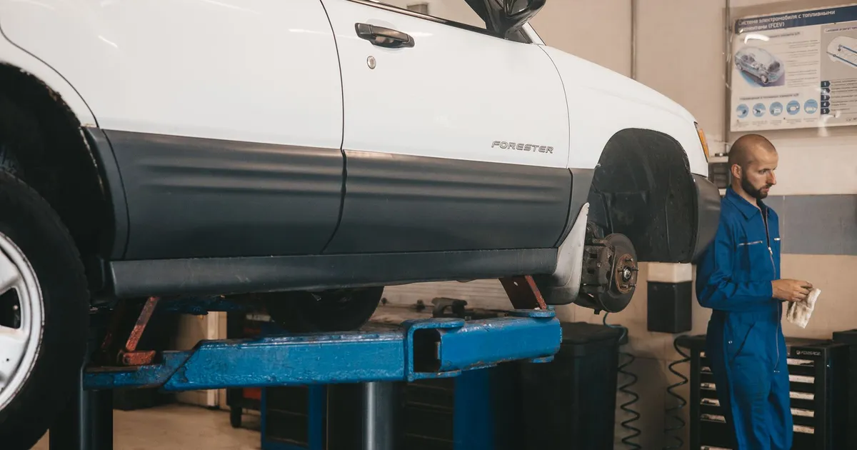 Mechanic evaluating a car on a lift for maintenance in an auto workshop.