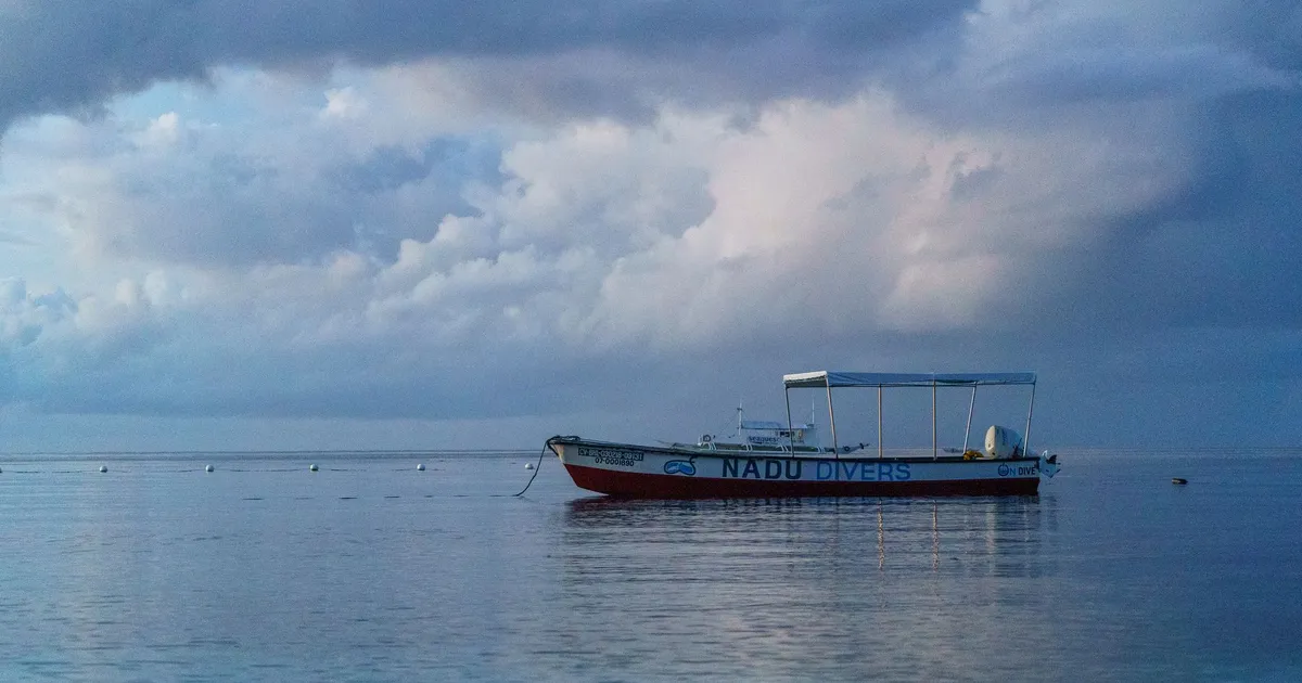Tranquil seascape featuring a lone boat, ideal for diving enthusiasts, under an overcast sky.