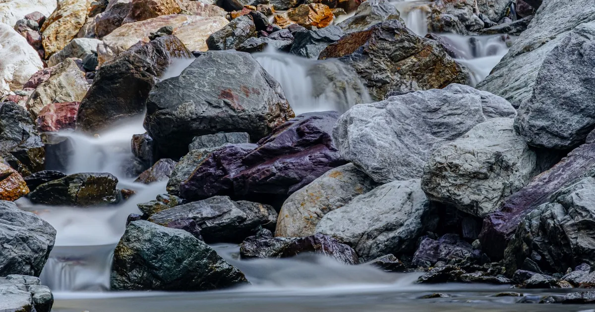 A beautiful waterfall cascading over rocks in a tranquil outdoor setting, creating a peaceful and calming scene.