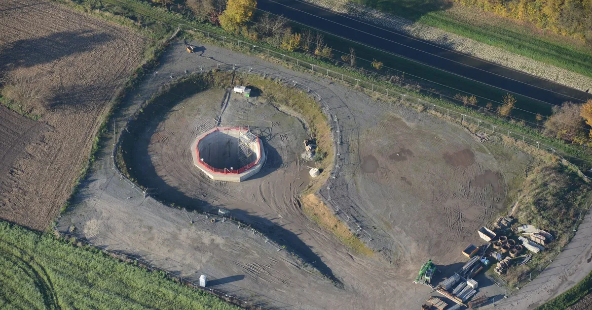 Aerial view of a small construction site amidst fields and trees during autumn.